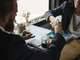 Two business professionals shaking hands over coffee after agreeing on a consulting engagement