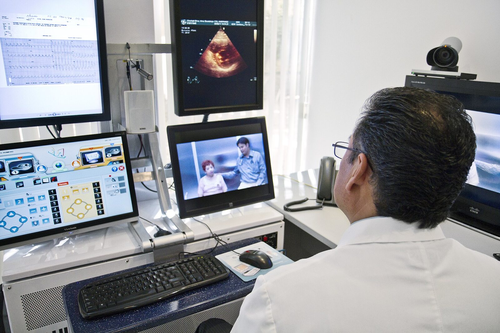 A physician at a multi-monitor computer workstation using digital health technology, representing AI for medical practices