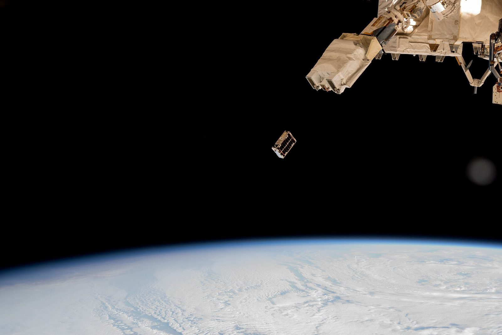 A CubeSat small satellite is ejected into Earth orbit from a deployer outside the International Space Station