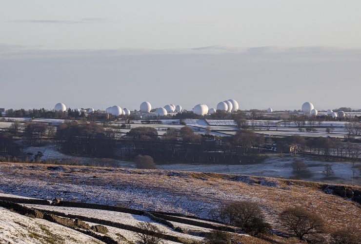 Rows of white radome domes at a sovereign signals-intelligence and satellite communications station, representing protected national network infrastructure