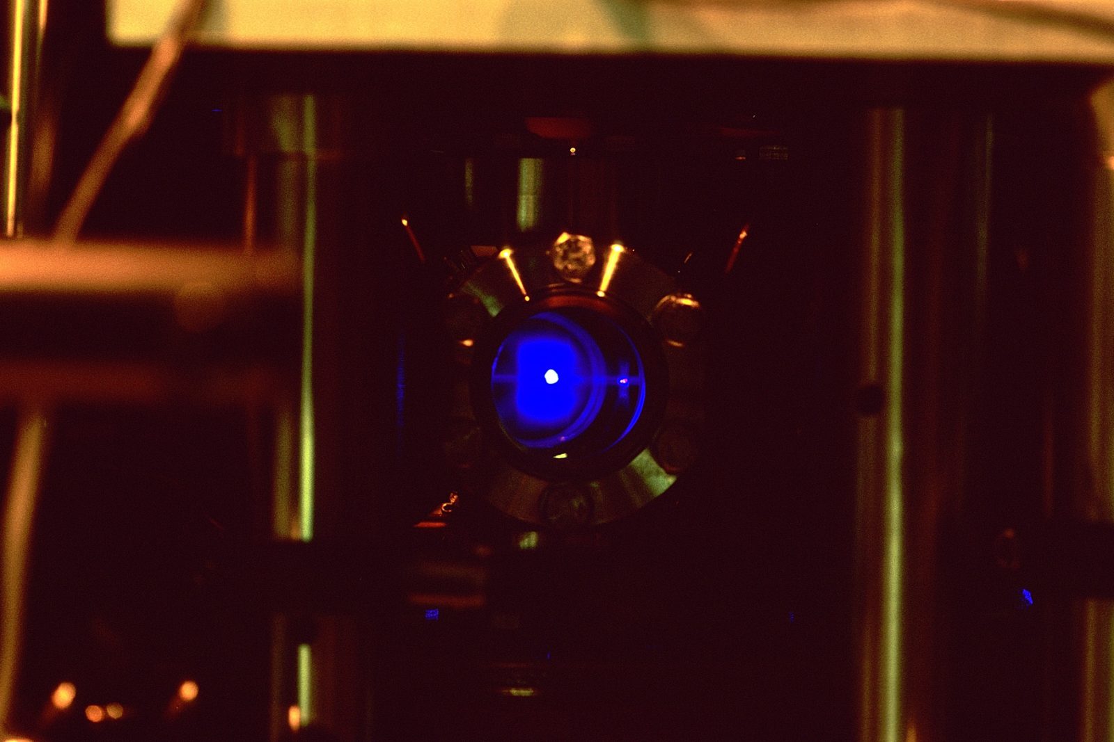 A strontium atomic clock lab setup showing a glowing blue cloud of laser-trapped atoms used to measure super-fine timing ticks