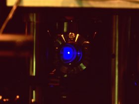 A strontium atomic clock lab setup showing a glowing blue cloud of laser-trapped atoms used to measure super-fine timing ticks
