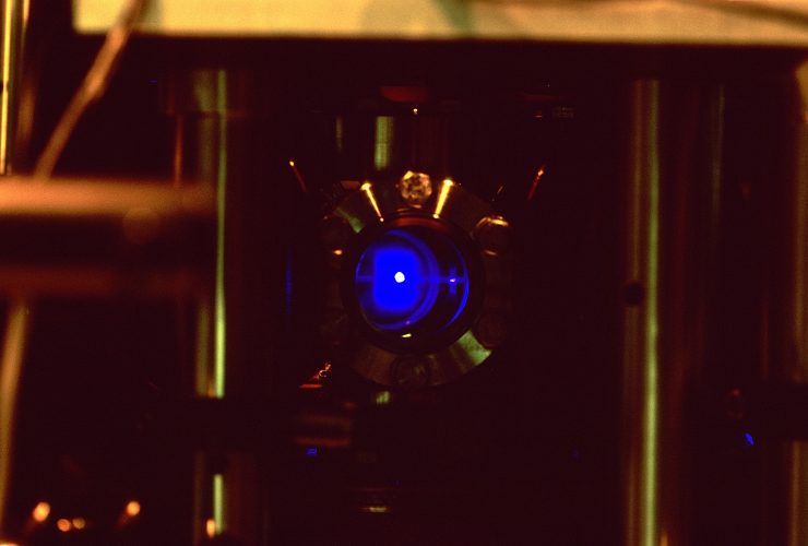 A strontium atomic clock lab setup showing a glowing blue cloud of laser-trapped atoms used to measure super-fine timing ticks